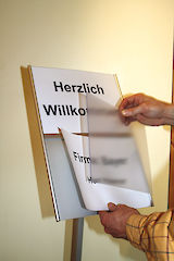 Wechsel des Einlegers in einem Primus Infoständer mit zwei separaten Feldern im DIN A4 Querformat