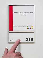 Türschild mit Braillebeschriftung (links) und taktiler Beschriftung (rechts)